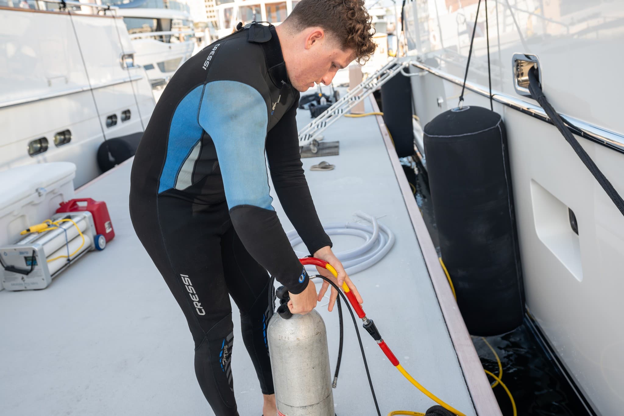 Diver on a boat deck connecting a scuba tank