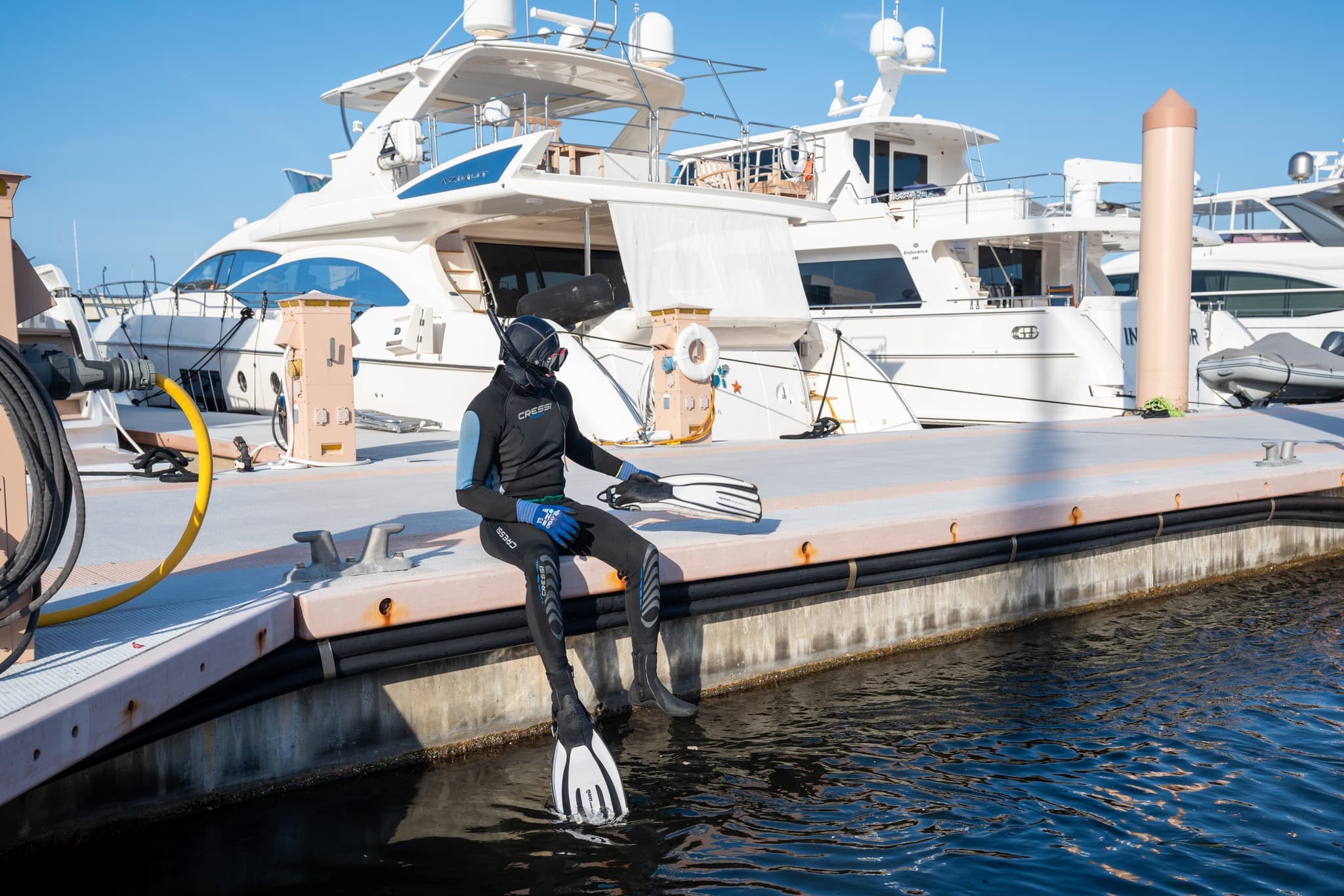 Diver seated on the dock with yachts in the background