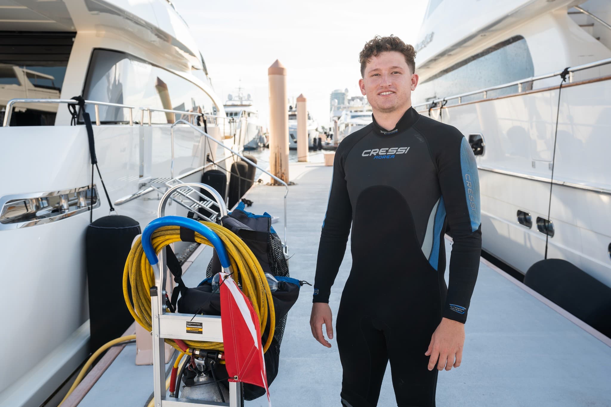 Diver standing on the dock beside a tank cart and dive flag