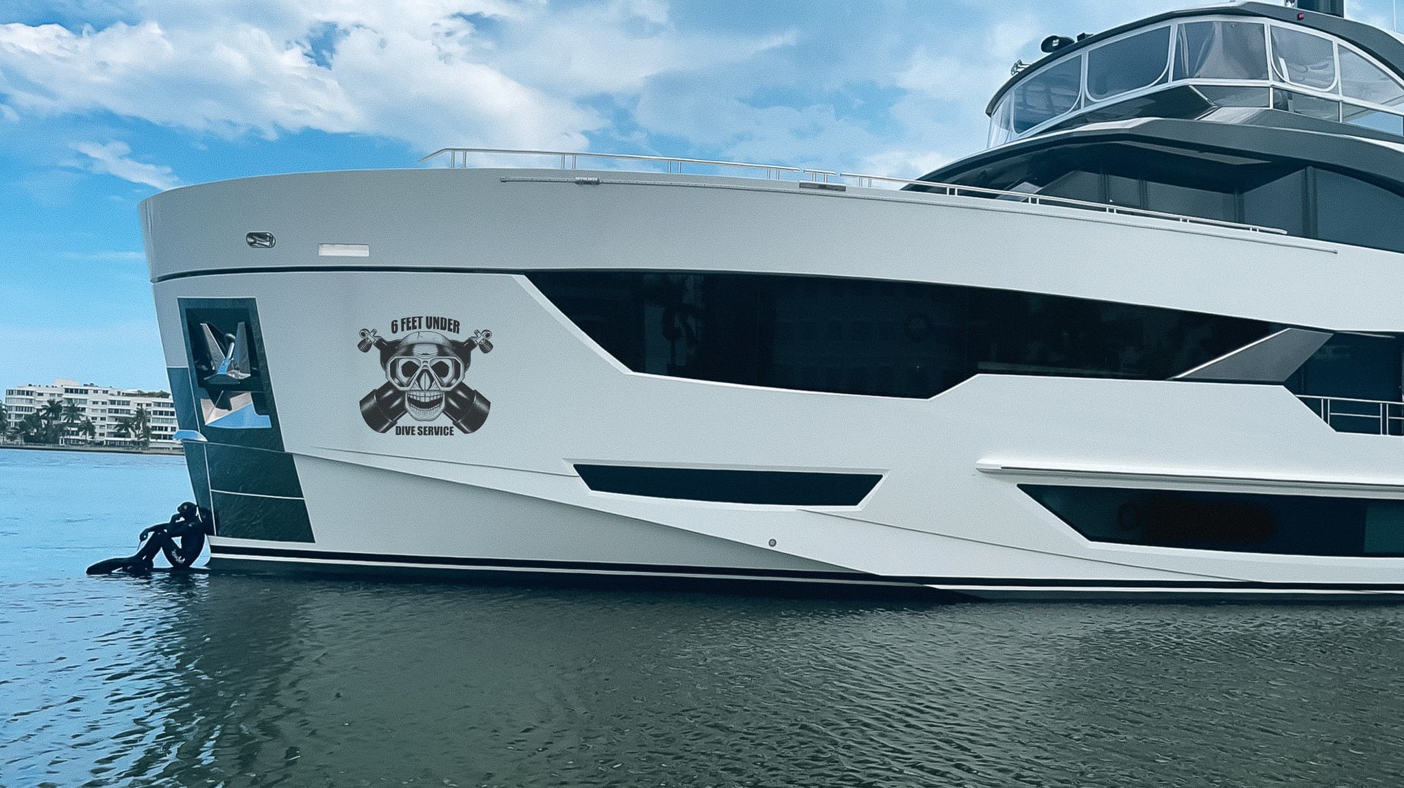 Motor yacht bow with the 6 Feet Under Dive Service skull logo on the hull