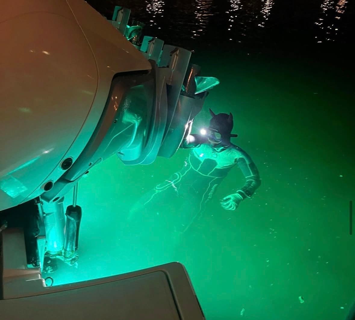 Diver working underwater beneath a boat hull